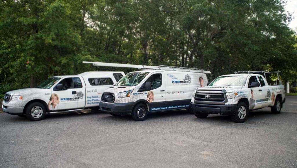 A fleet of Screenmobile service vehicles — a pick up truck, a service van, and a truck with camper